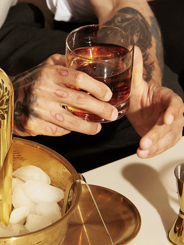 Man holding a drink with a Gold Daddy Vodka bottle and a strawberry cocktail on the table, featured on a banner