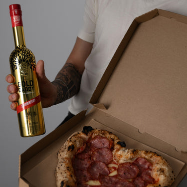 Heart-shaped Valentine’s Day pizza with a hand holding a bottle of Gold Daddy Strawberry Kiss liqueur